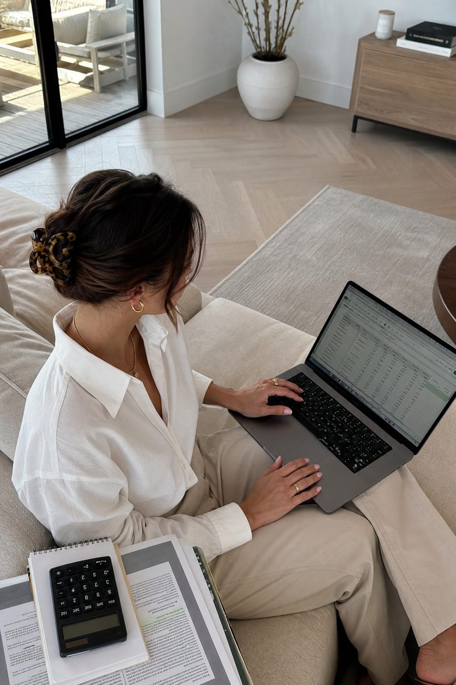A woman at a desk with a laptop and a calculator, working on her money