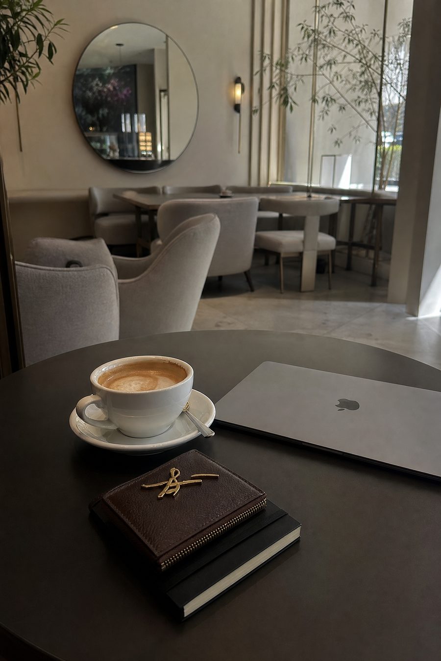 A coffee, a laptop and a leather journal on a quiet cafe table